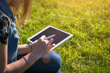 女孩电脑平板电脑在外面工作在夏季自然公园使用商务在线技术进行户外活动的女学生带笔记本电脑的人快乐时髦的年轻背景图片