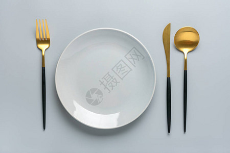 灰色桌子上空的白色圆盘叉子刀勺子顶视图平铺早餐午餐或晚图片