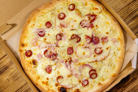 美味的新鲜比萨在木桌上的纸板箱里顶视图送货上门的概念图片