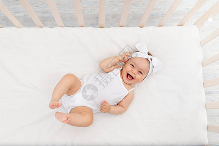 个月大的女婴躺在托儿所的婴儿床里背景图片