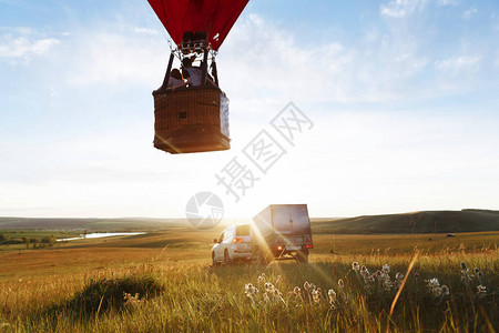 红热气球心形在山谷着陆或起飞背景图片