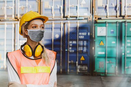 女工业程师戴着安全帽和嘈杂的防护设备在户外工作场所容器产品中戴上口罩以保护冠状Covid1背景图片