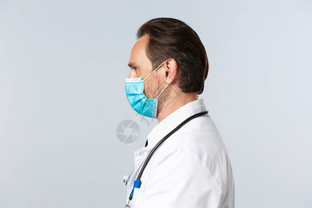 医疗面具和白大衣中严肃执着的医生对病人进行检查图片