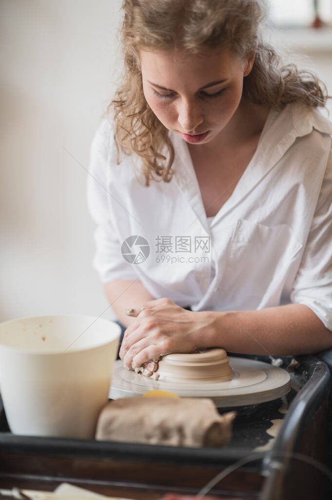 工作室用泥土在轮子上工作的女洗手匠Clay用水喷满了陶器轮图片