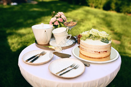 餐桌设置陶瓷茶壶茶杯蛋糕和鲜花特闭式图片