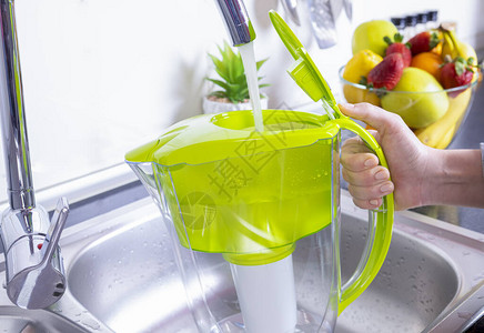 厨房中妇女填水过滤罐饮用水自来水净化和软图片