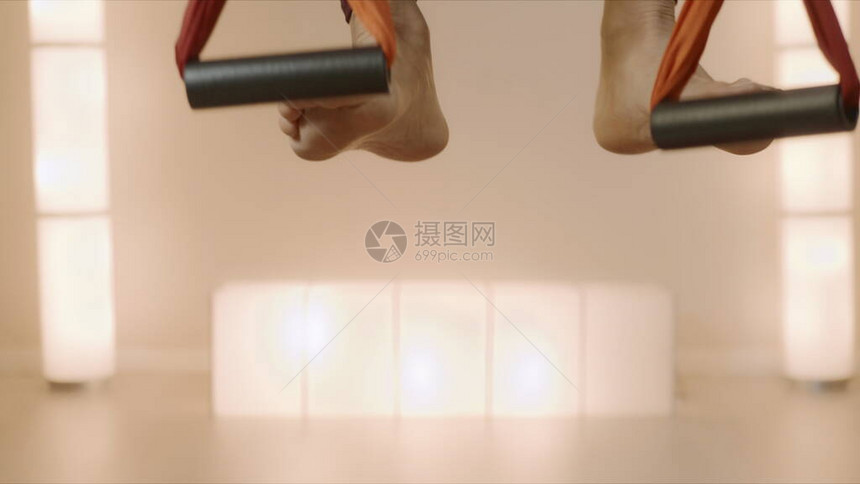 关闭在运动服的女人在锻炼前把脚伸进瑜伽带女体操运动员在瑜伽馆的吊床上伸展身体健身女孩在吊床上图片