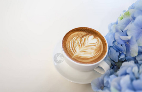 白色桌边的白杯热咖啡拿铁和奶泡沫心脏形状艺术图片