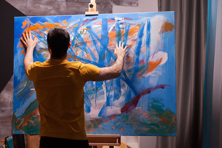 艺术家用指尖在艺术工作室的大画布上绘画图片