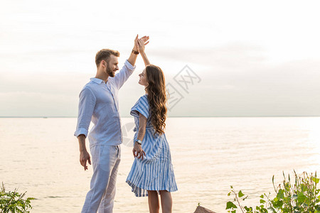 快乐的情侣牵手在湖边跳舞图片