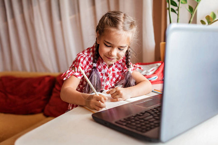 可爱的学童在家上网课时学习作业图片