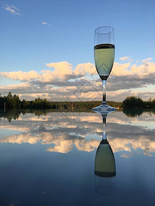 一杯白葡萄酒反映在玻璃桌的镜面上图片