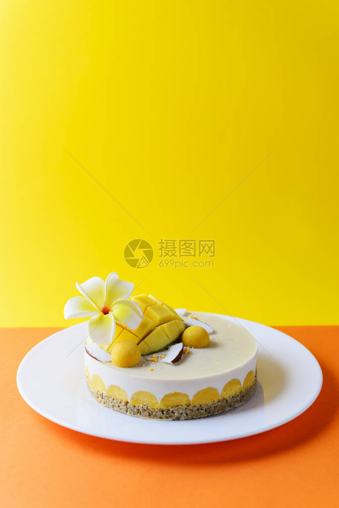 腰果蛋糕与芒果和椰子在黄橙色背景图片