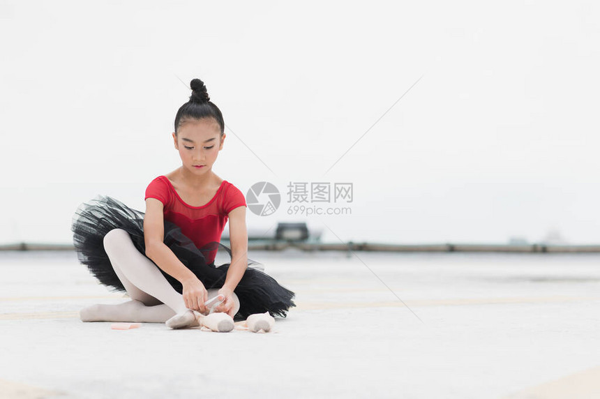 亚洲芭蕾舞女演员在练习芭蕾舞前系足尖鞋带图片