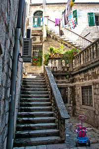 通往前门绿色庭院的楼梯在一个历史悠久的地中海小镇的晾衣绳上放着儿童玩具和晒衣服背景图片