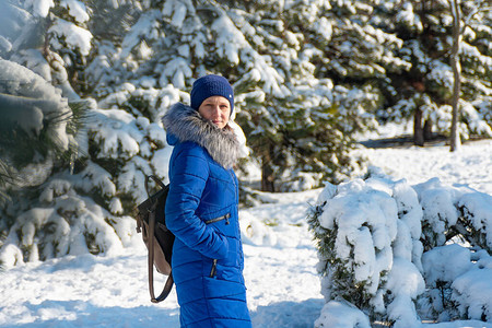 冬天穿蓝衣服的女孩在雪地松林里享受着寒冷的大自然图片