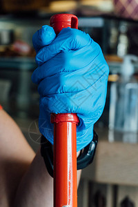 戴着蓝色手套的女人用拖把清洁餐厅的地板图片
