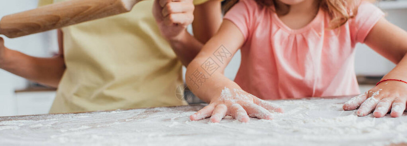 女儿在厨房桌子上撒面粉时的部分外观背景图片