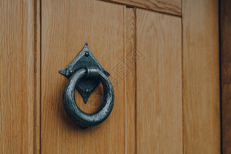 关闭房子的木制前门上的铁门环图片