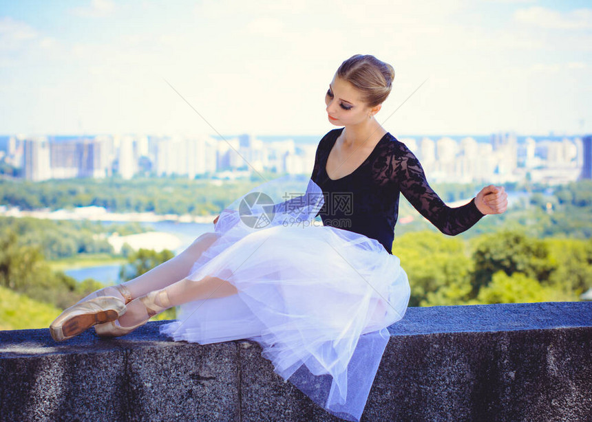 穿着白色芭蕾舞短裙的年轻女子在绿色景观中跳舞美丽的芭蕾舞女演员向空中展示经典芭蕾姿势女温柔与和谐生活的概念芭蕾图片