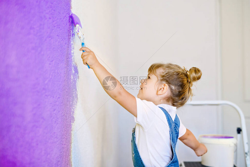 有趣的蹒跚学步的小女孩在新房子里用颜色粉刷墙壁家庭维修公寓的家快乐的宝贝孩子画墙图片