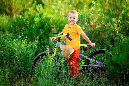 穿着橙色衣服的快乐小男孩在夏天坐在绿色草地图片