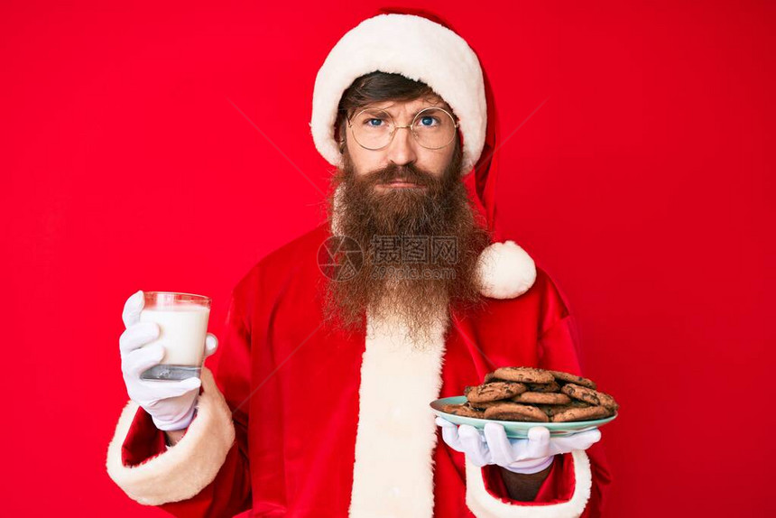 穿着圣达克萨斯服装长胡子的英俊年轻红头男子拿着饼干和牛奶图片