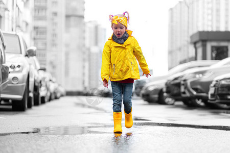 穿着黄色雨衣和穿橡胶靴的可爱女孩图片