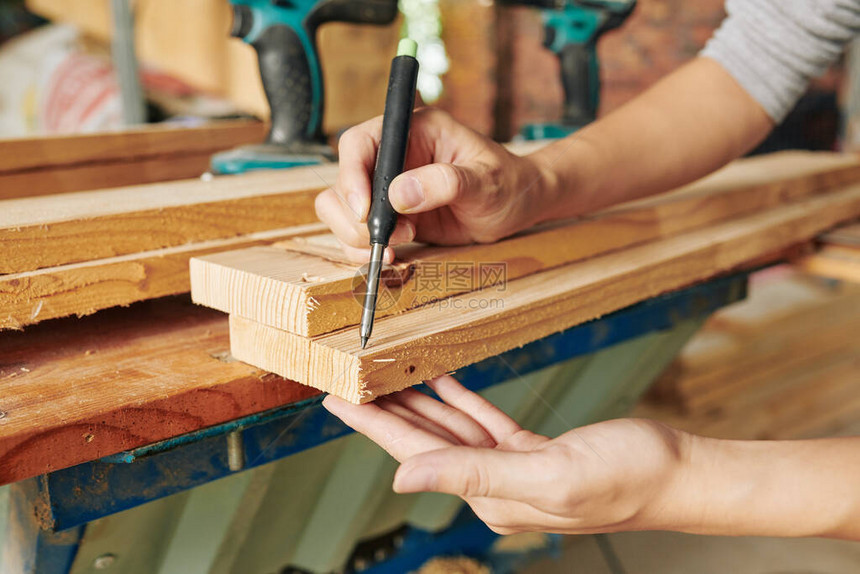 木匠在剪切长木板和制造家具装置之前在长木板上画标图片