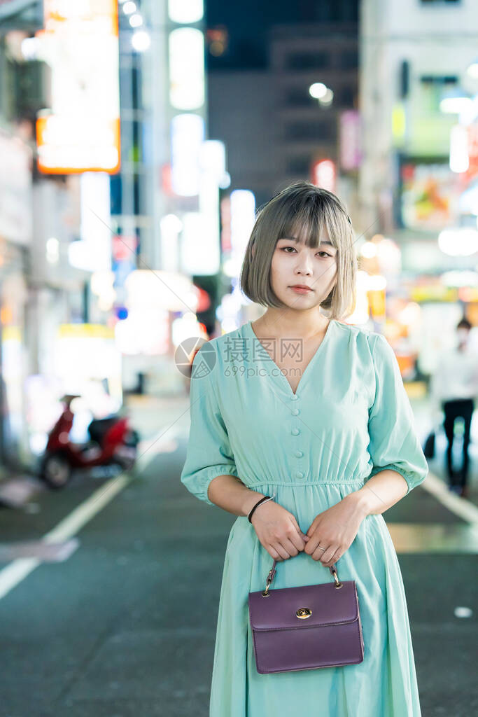 年轻女人在夜里在东京闪亮的城图片