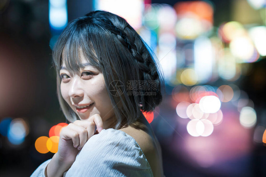 年轻女人在夜里在东京闪亮的城图片