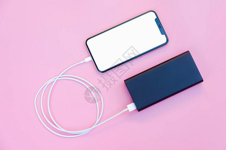智能手机在粉红色背景下使用移动电源充电图片