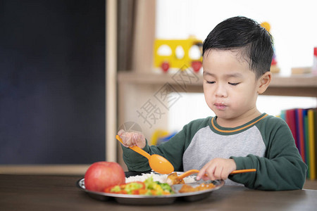 亚洲学生在教室里用学前班准备的食物托盘吃午餐背景图片