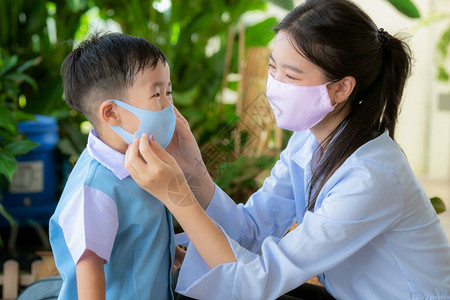 亚洲母亲在上学前使用面罩保护她的儿子图片