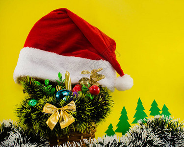 照片由圣诞花篮装饰球圣诞帽子和黄色背景的首饰组成图片