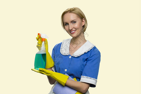 漂亮微笑的管家拿着清洁喷雾显示瓶洗涤剂的妇女清洁剂反对白色背景专业图片
