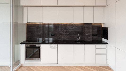 现代住宅的全景立面景观与现代室内设计在白色厨房橱柜家具内置家用电器水槽水龙头电烤箱背景图片