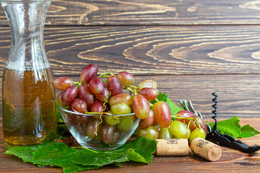 大而轻的酿酒葡萄它覆盖着一层叫做酵母的白色涂层杯子里装满了淡酒浆果上的水滴在一个木制的背景图片