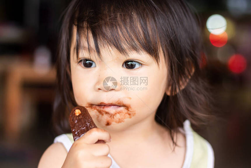 1到2岁小孩的肖像快乐的亚洲女孩独自吃冰淇淋棕色巧克力她的脸图片