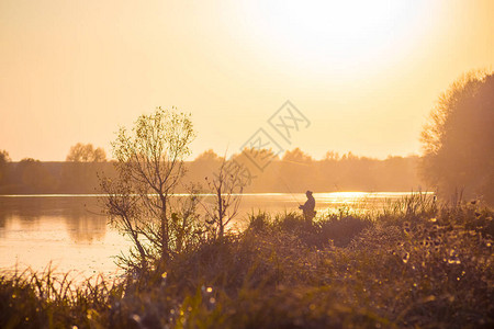 日落时河岸的风景与河流树木和渔民图片