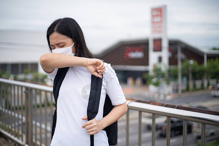 身着防护面罩戴防毒和污染面具咳嗽和站在横越城市街道的亚洲妇女图片