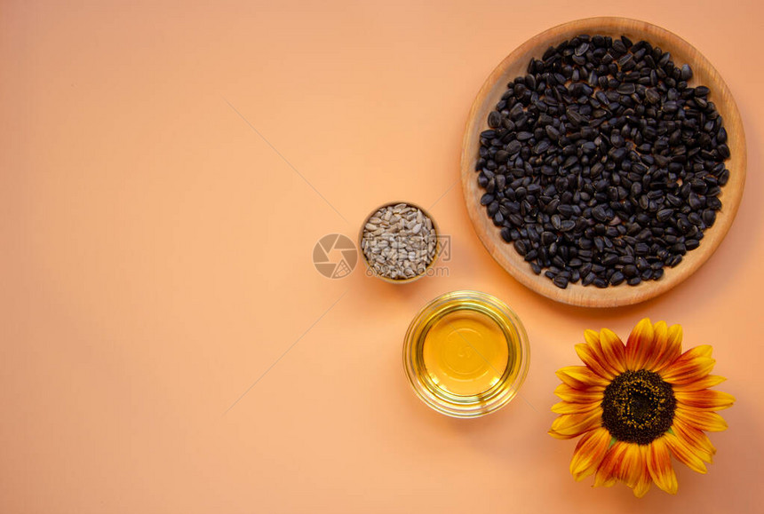 具有向日葵油种子向日葵花的浅橙色背景的创意平铺组合物健康食品的概念平图片