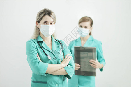 两名女医生或护士戴医疗面罩盯着照相机看图片