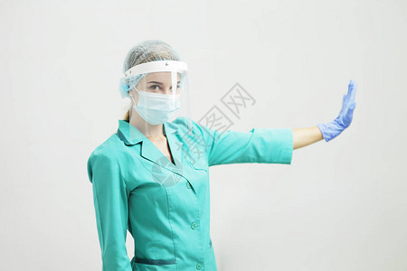 身穿制服戴医疗面具防护盾和手套的女医生或护士手持势停止图片