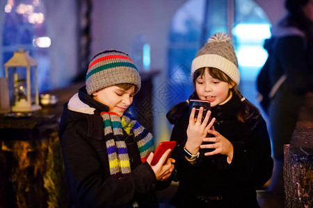 男孩和女孩在大雪期间在传统的圣诞市场上玩得开心图片