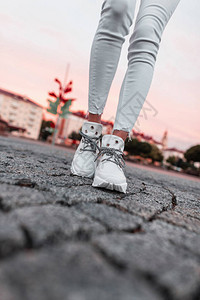 穿着白色运动鞋的时装女腿和穿牛仔裤在市内粉色图片