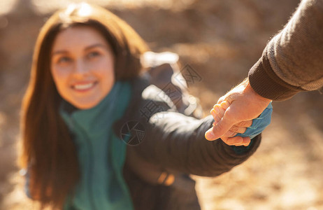 快乐的年轻女子在前往森林远足时向男人伸出双手图片