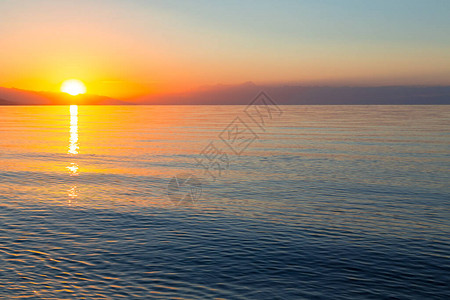 水面初凝海上太阳的黎明山后初升的太阳背景