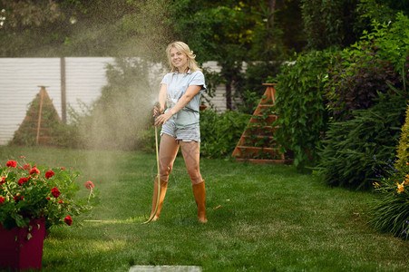 有吸引力的女园丁用软管在花园里浇水女人在户外照顾鲜花园艺爱好花店生图片