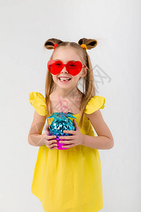 心形太阳镜的快乐小女孩拿着菠萝玻璃隔离在白色背景上图片